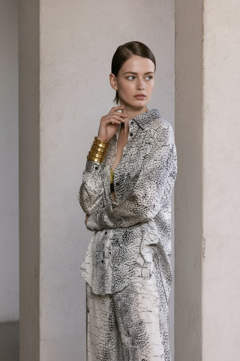 Woman wearing a patterned outfit standing against a neutral wall.