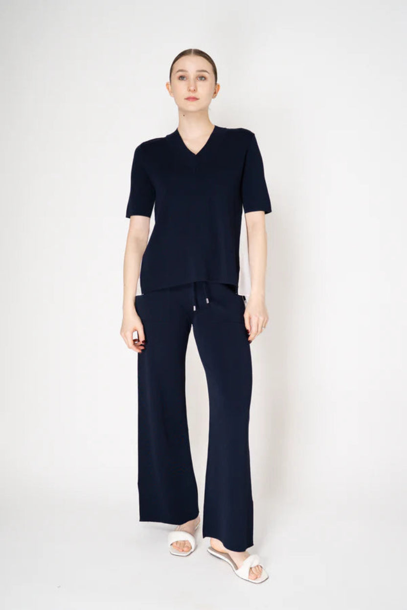 Woman wearing a navy outfit with a top and wide-leg pants on a white background.