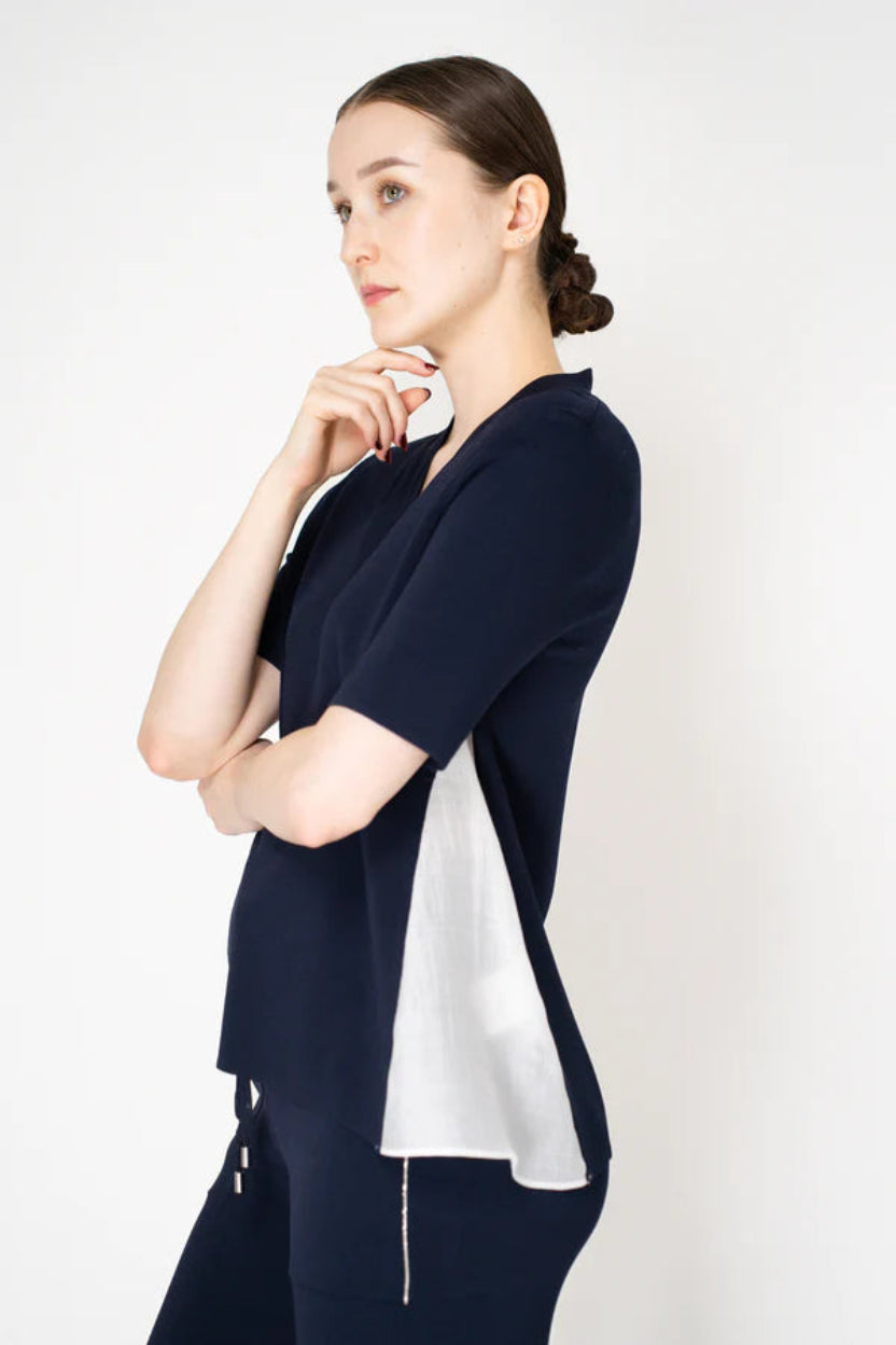 Woman wearing a navy blue outfit with a white panel on a white background.