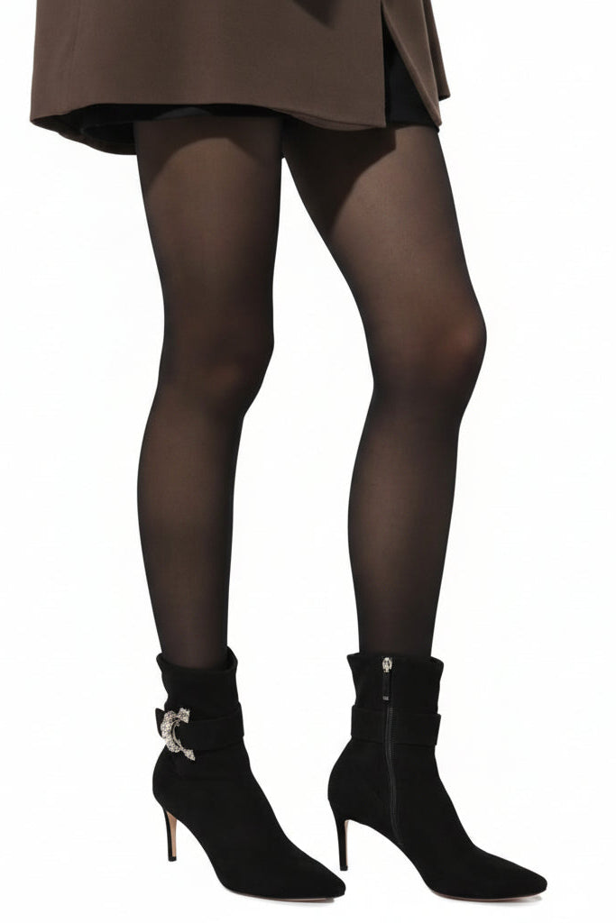 Person wearing black tights and high-heeled shoes on a white background