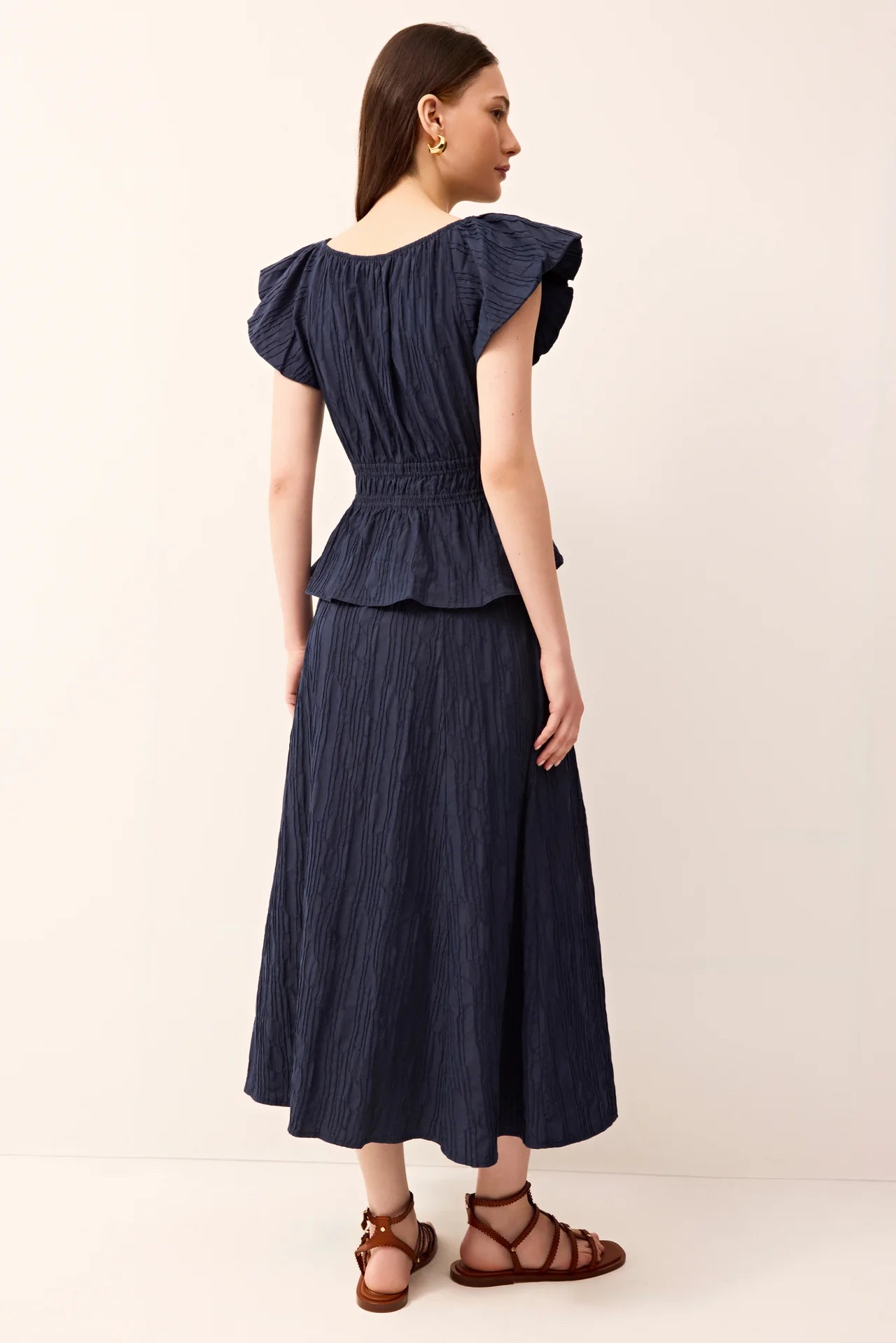 Woman wearing a navy blue top and skirt on a white background.