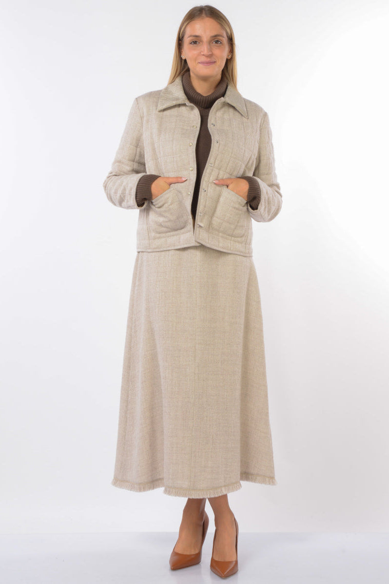 Woman wearing a beige coat and skirt set on a white background.