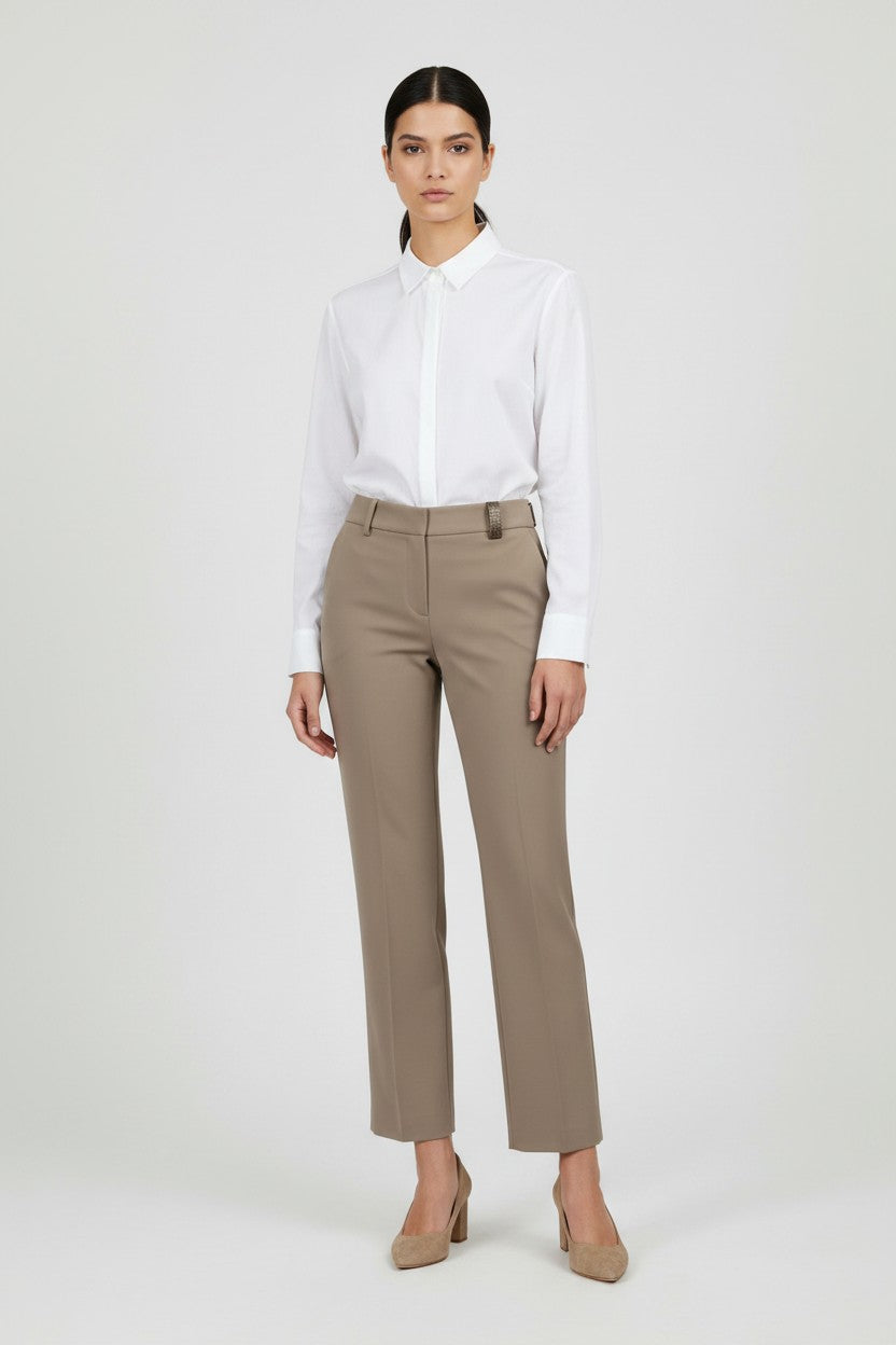 Woman wearing a white shirt and beige pants on a white background.