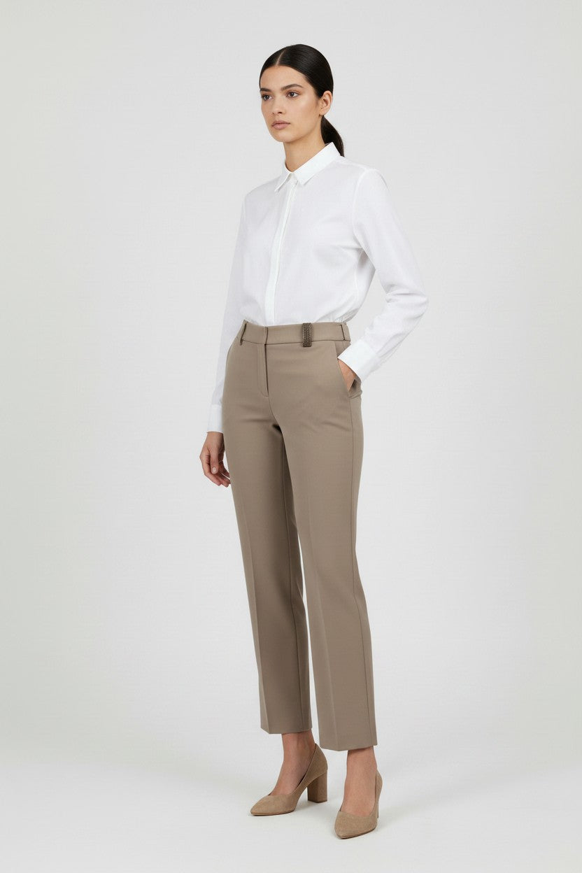 Woman wearing a white shirt and beige pants on a white background.