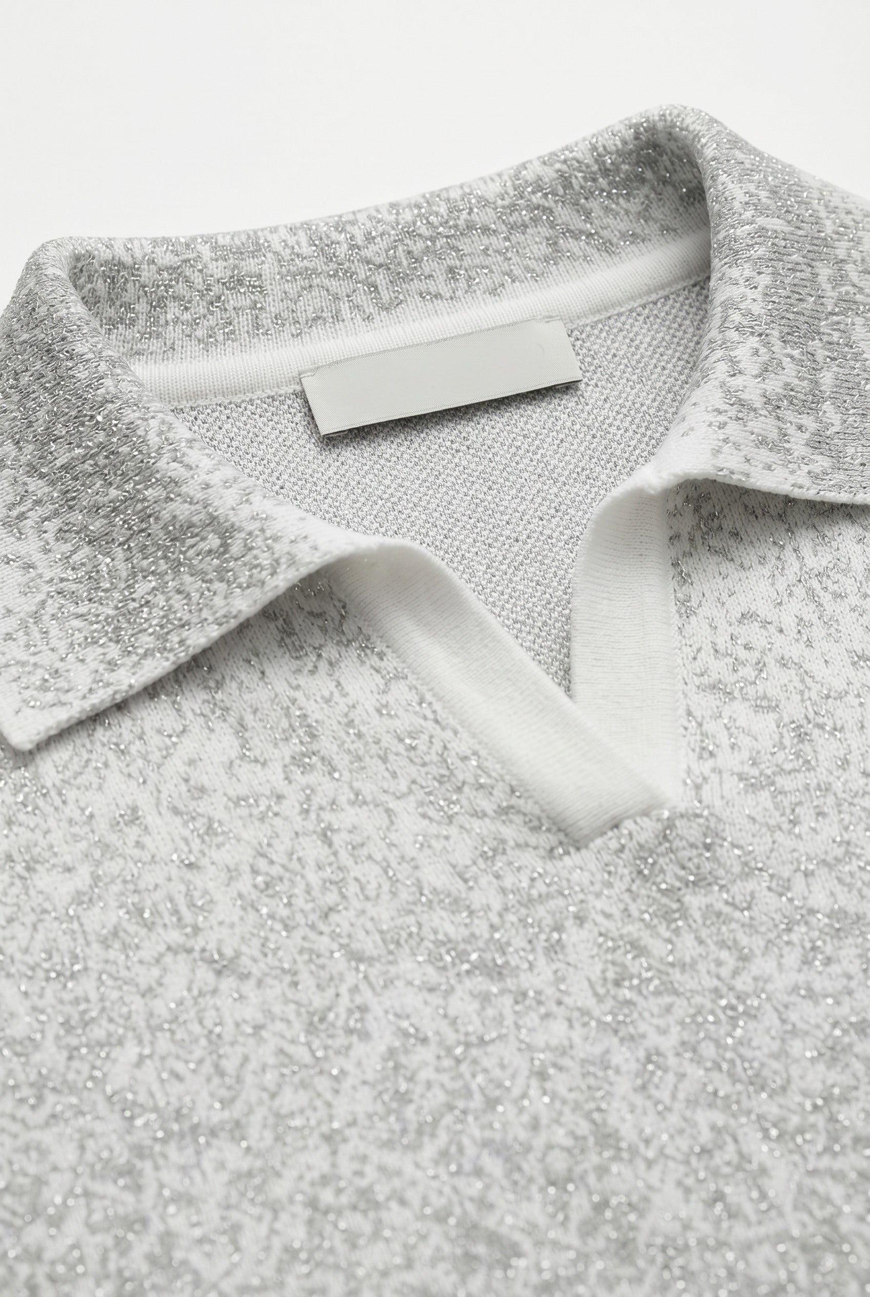 Close-up of a gray and whiote shimmer polo on a white background.