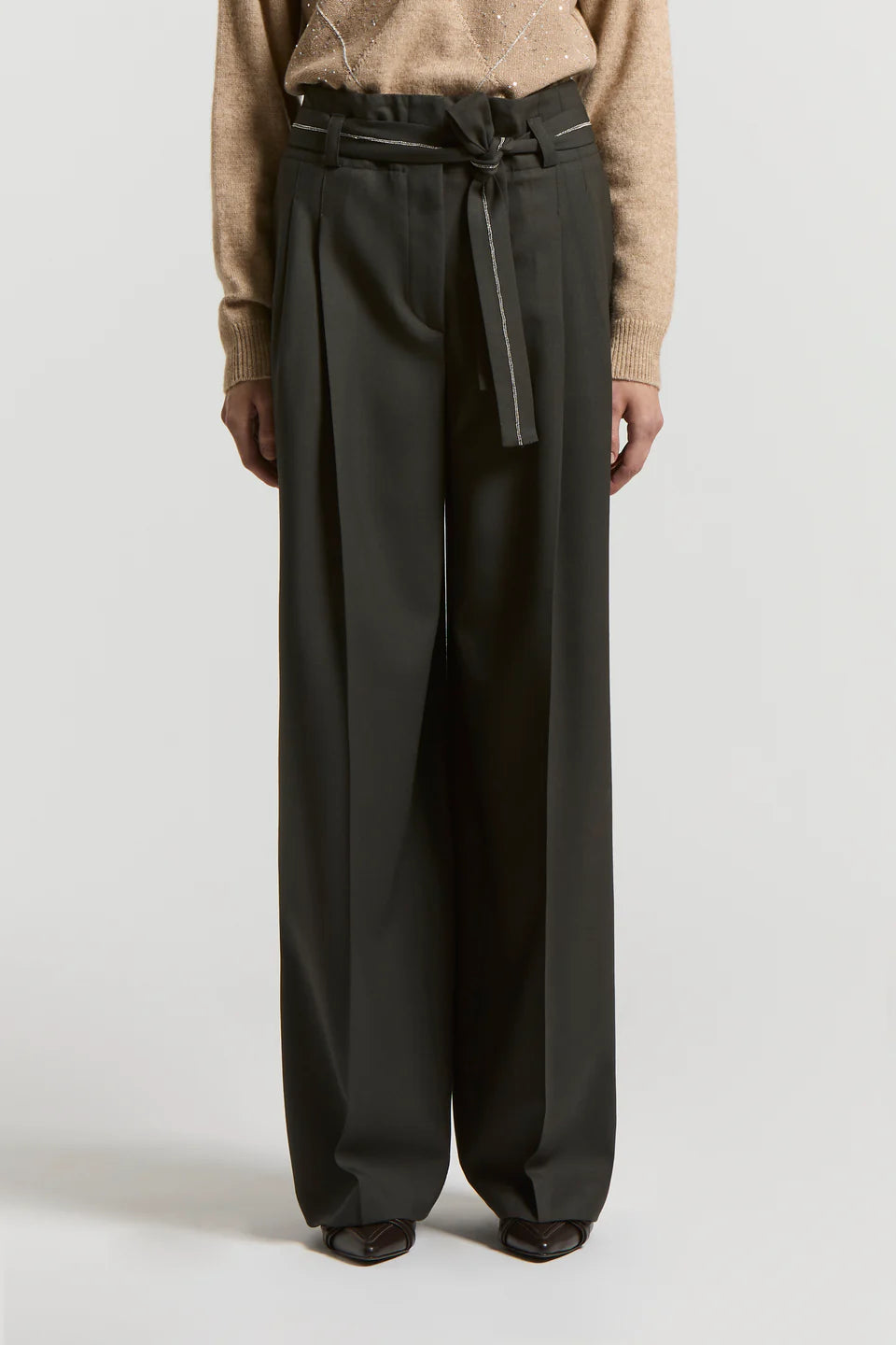 Woman wearing black wide-leg pants with a sparkle belt  on a light background.