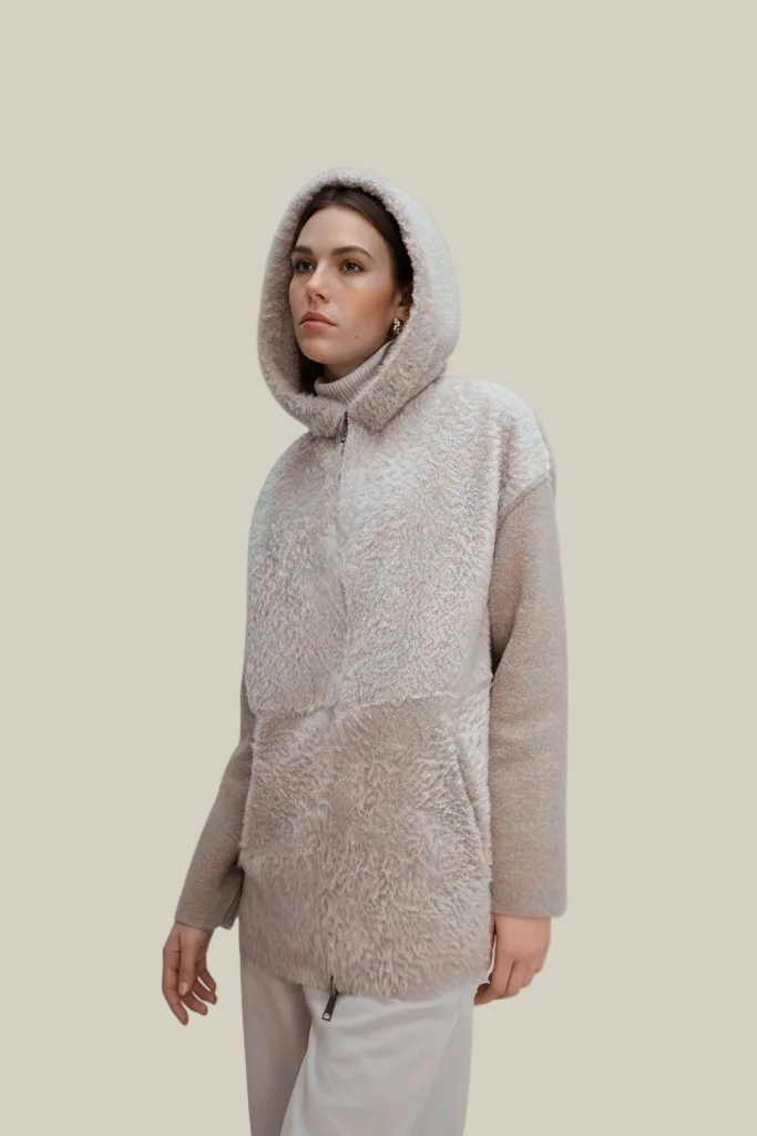 Person wearing a beige hooded sweater on a plain background