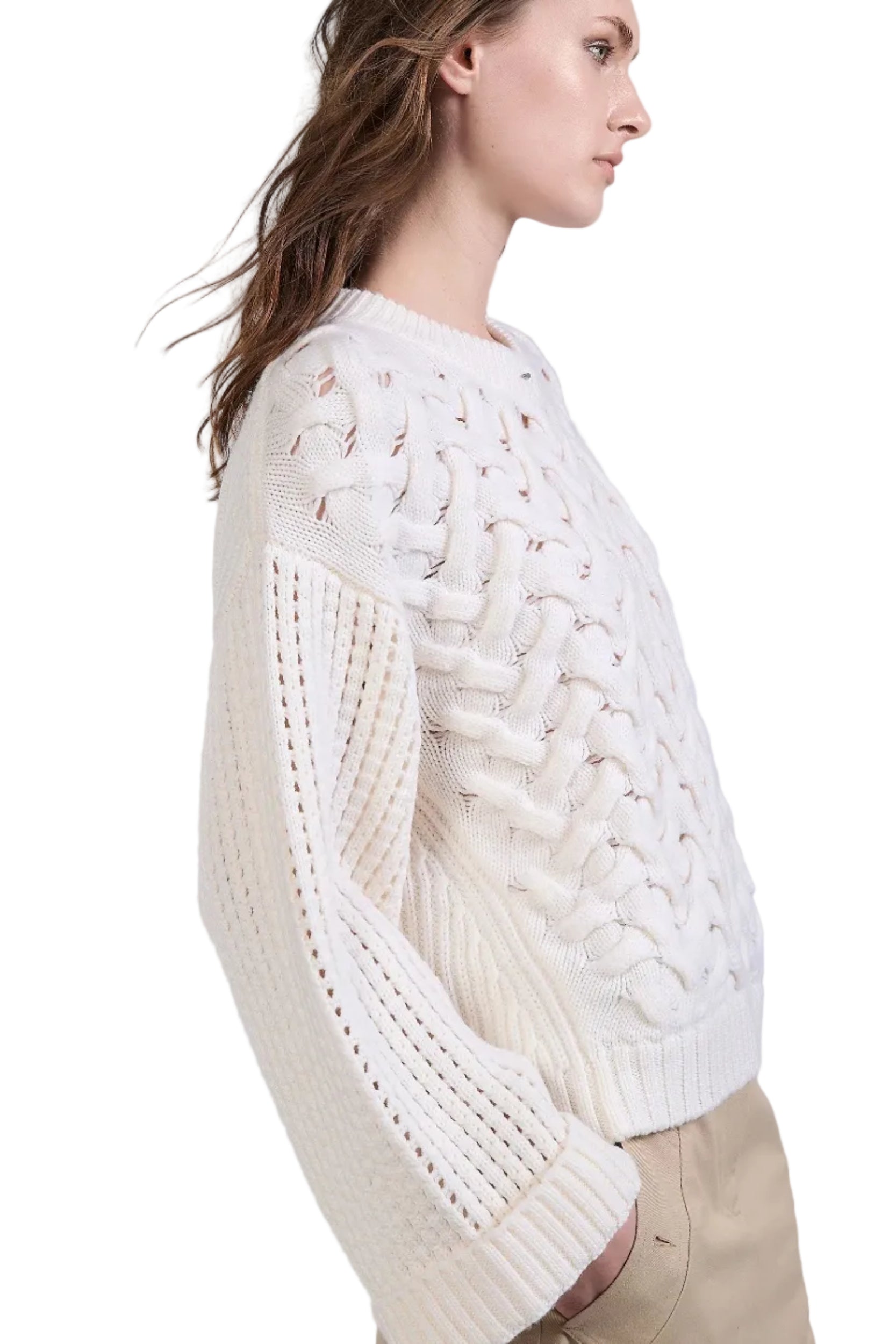 Woman wearing a white cable knit sweater on a light gray background.