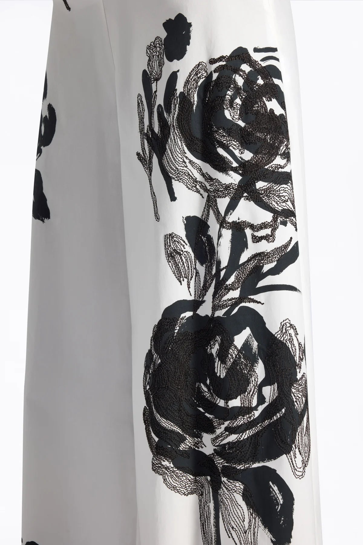 White fabric with black floral embroidery.