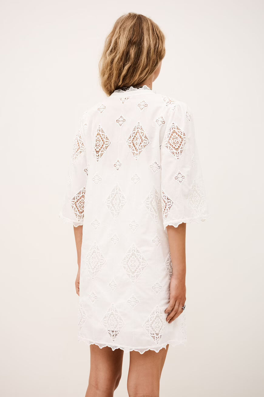 The back of a woman wearing a white lace dress against a plain background.