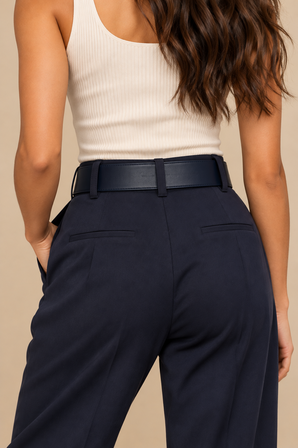 Back view of the Gavazzeni Angelica navy blue leather belt featuring a smooth, wide leather strap, styled through the belt loops of navy tailored trousers with an ivory ribbed top.